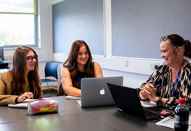 Teachers sitting around a table with laptops