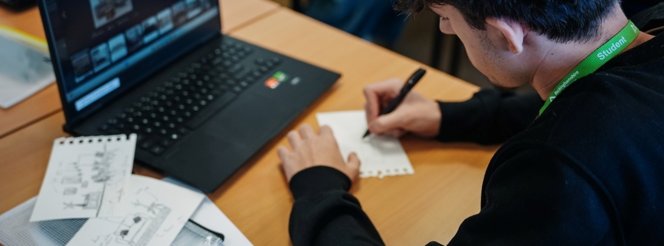 Student writing in front of laptop 