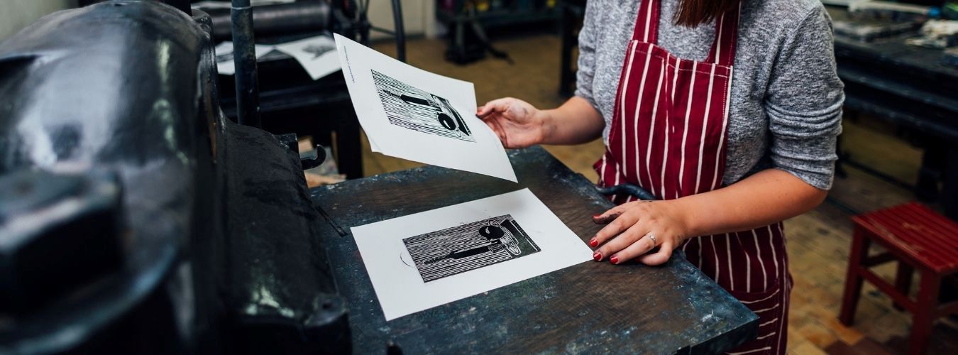 Person holding prints next to print machine