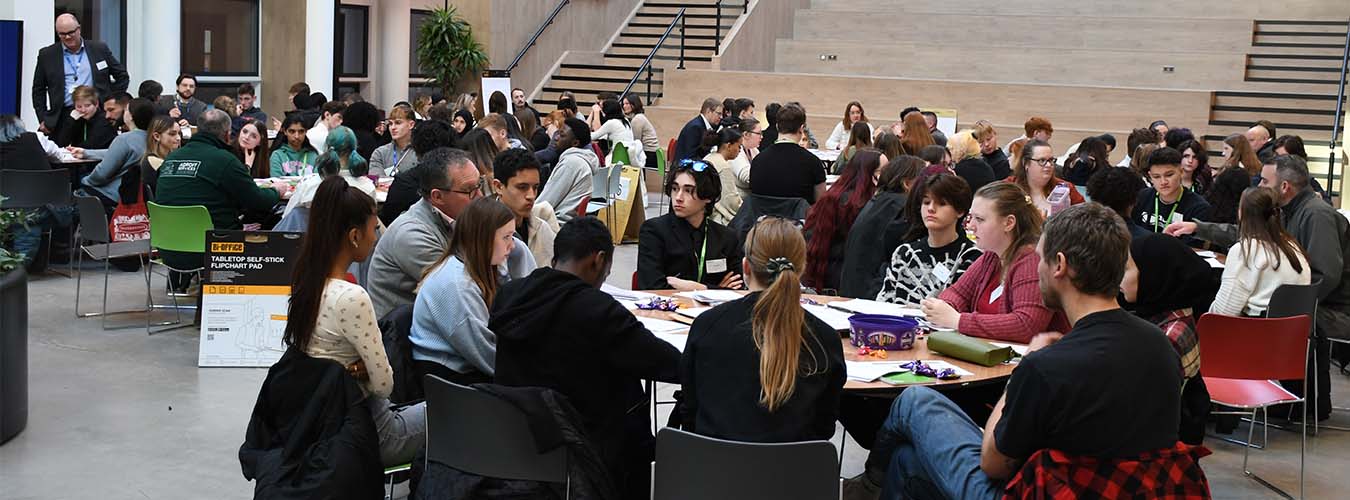 Students sat around table with employers in large hall