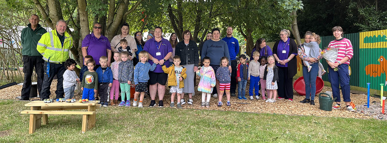 Nursery children, parents and staff standing in Nursery garden 